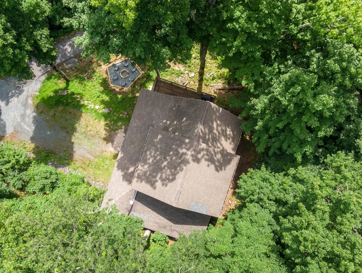 This exterior shot highlights the peaceful backyard, with the fire pit as a focal point surrounded by trees, offering a secluded and serene setting for guests to relax or entertain after a day of winter activities.