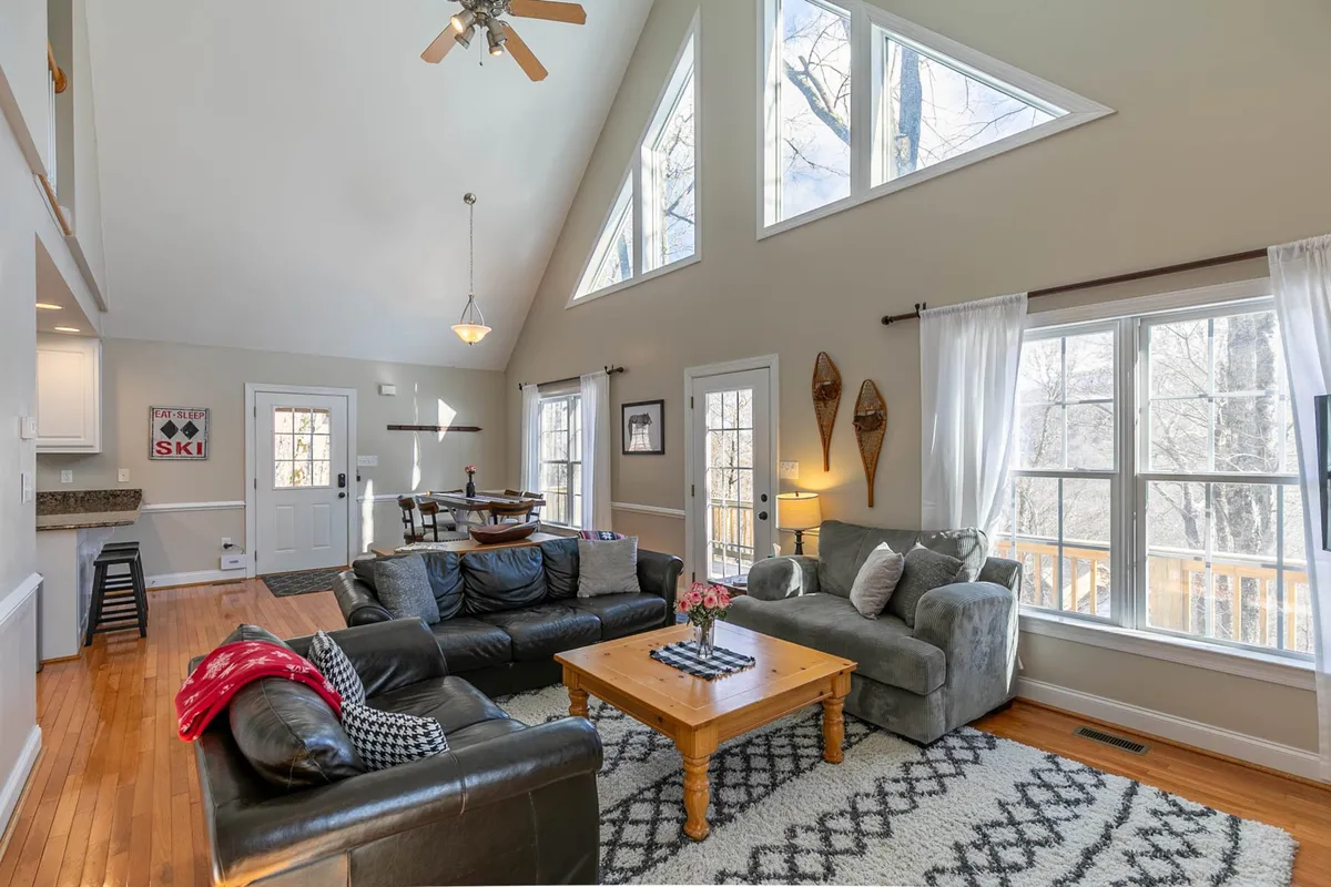 This image features a spacious living area filled with warm natural light from large windows. A central coffee table adorned with fresh flowers anchors comfortable seating that invites relaxation, socializing, and family bonding. The overall mood is welcoming and homey, underscoring the comfort and ease promised in the section.