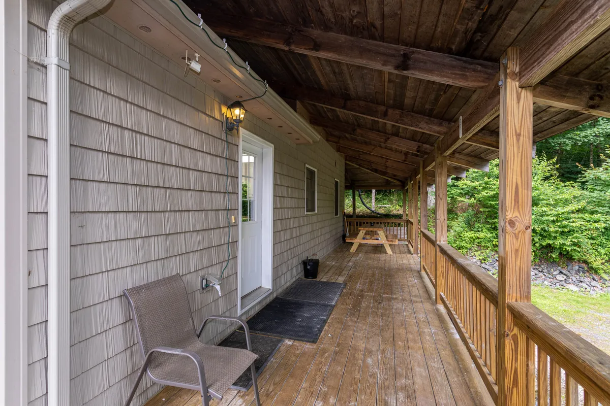 A wooden deck equipped with a picnic table and a chair, set against a backdrop of natural greenery and mountain views. The space invites guests to relax, enjoy meals outside, and take in the scenic surroundings—ideal for unwinding post-adventure.